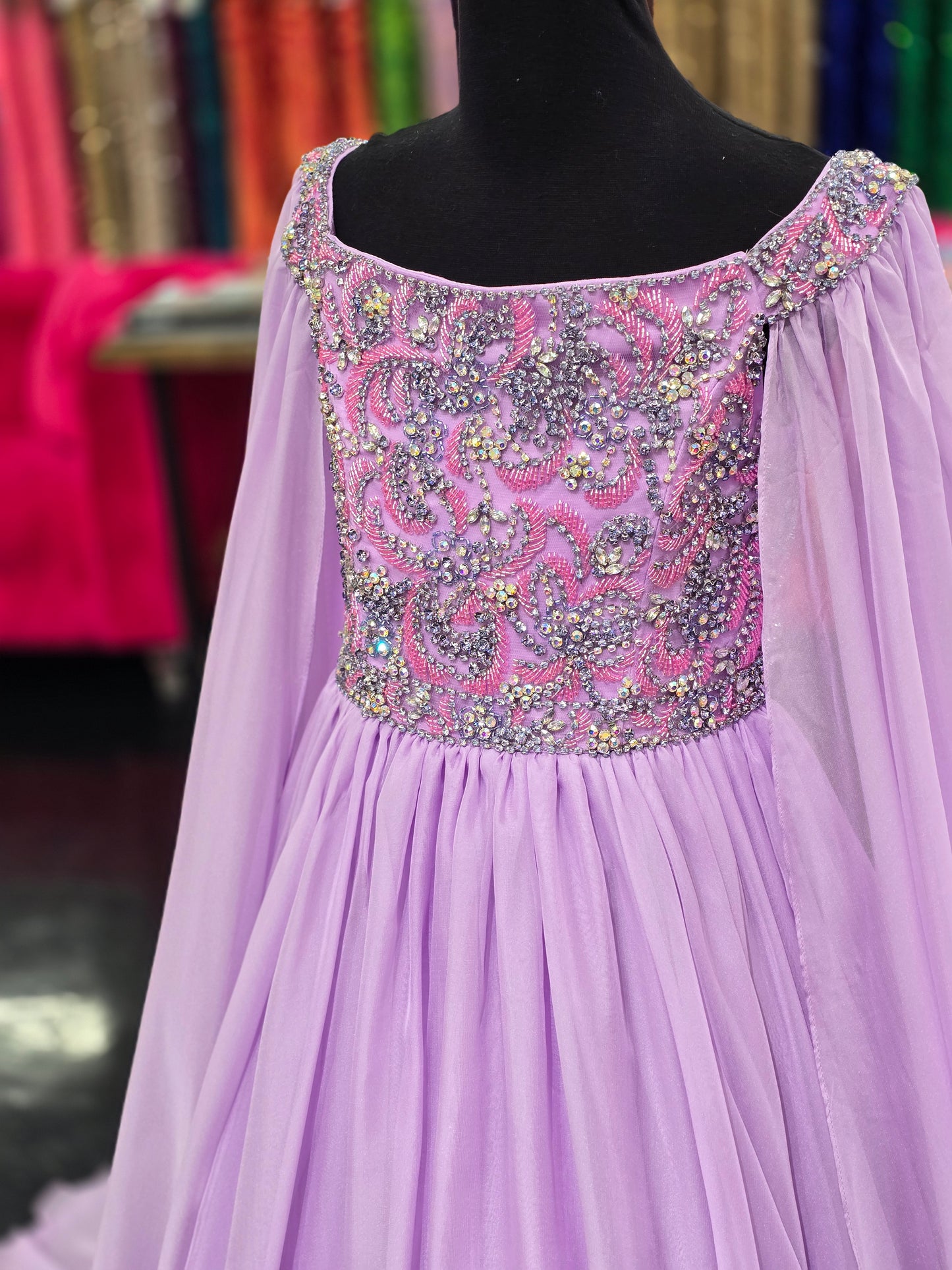 The Samantha Blade 1022 Girls Pageant Dress is the perfect choice for your little one's big day. With a stunning beaded crystal bodice and off-the-shoulder cape sleeves, she'll shine like a star. The chiffon ballgown train adds a touch of elegance and ensures she'll make a grand entrance.