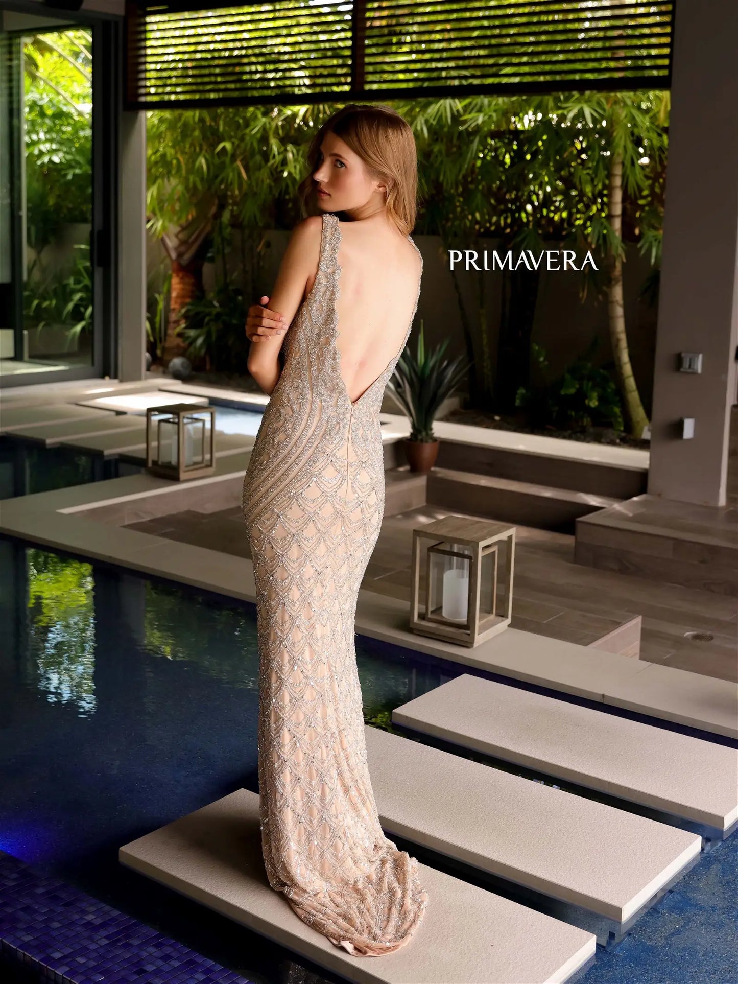 Get ready to turn heads in the elegant Primavera Couture 12102 Long Beaded Formal Evening Dress! With a stunning sequin design and scallop V neck, this backless prom gown will make you stand out from the crowd. Get ready to feel confident and glamorous at any formal event.  Sizes: 000-18  Colors: Nude Silver, Coral