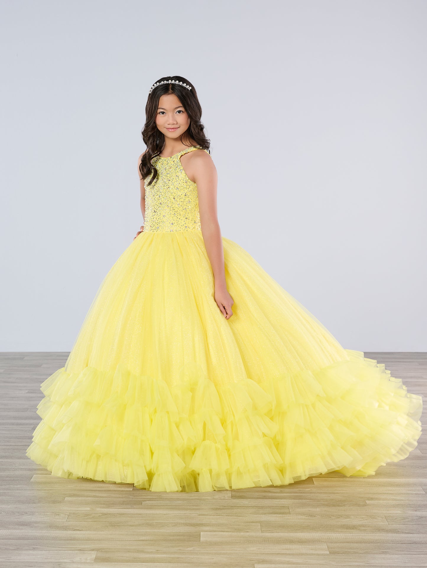 This Tiffany Princess pageant dress (style 13795) features a high neck, crystal embellishments, and a backless corset. The ruffle tulle skirt adds a touch of elegance, while the corset provides a secure fit. Perfect for any pageant girl looking to make a statement on stage.