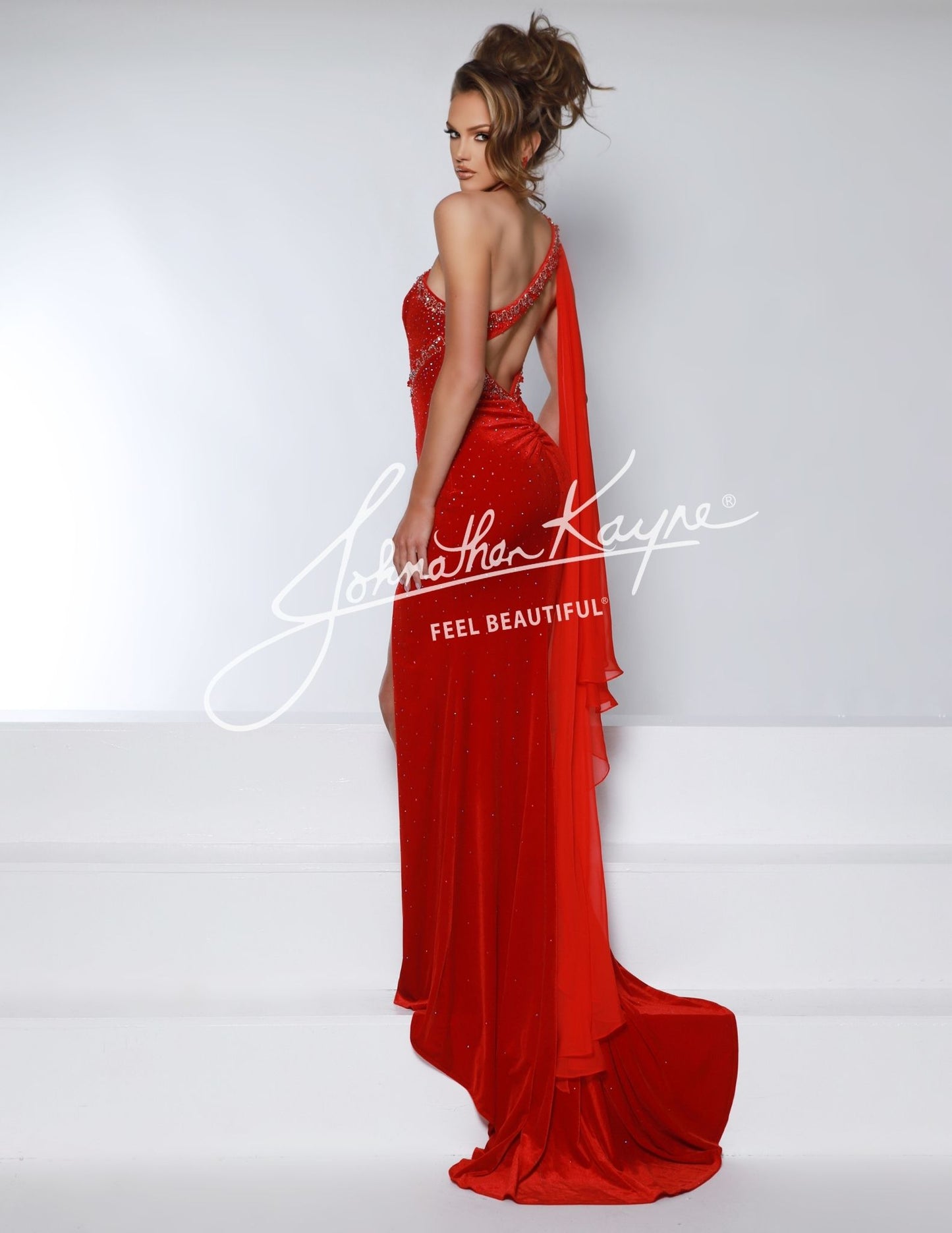 This Johnathan Kayne 2963 Velvet One Shoulder Pageant Dress features a stylish cape, one shoulder design, and a cutout back with a slit. The velvet material adds a touch of luxury, making it perfect for formal events. Be the star of the show in this unique and elegant gown.