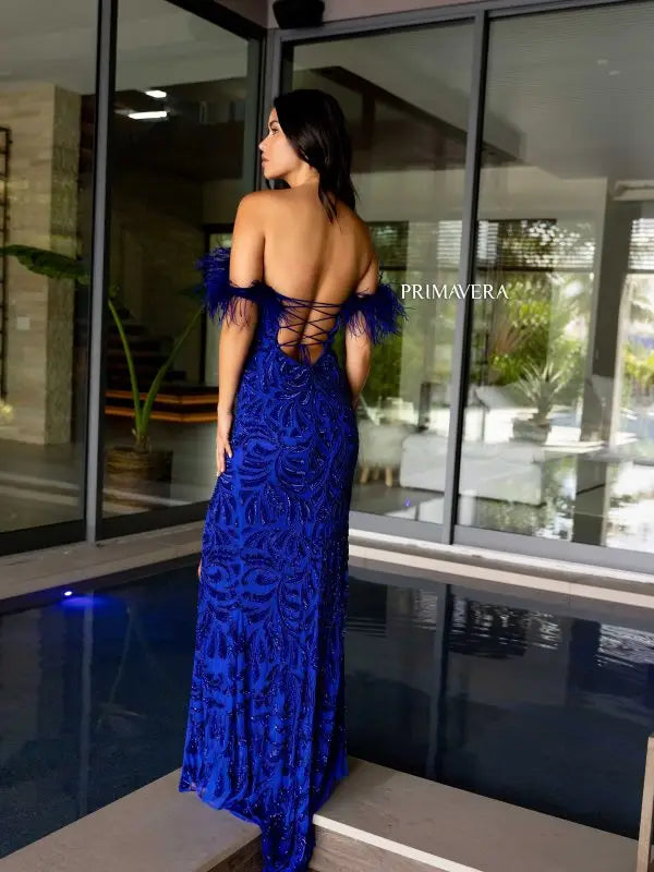 Elevate your style game with the Primavera Couture 4105 Long Prom Dress. Showcasing an off-shoulder design, this gown features a corset bodice adorned with feathers, sequins, and beads. Fitted and featuring a high slit, this formal pageant gown is perfect for making a statement at any event.