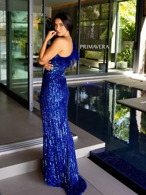 Elevate your style with the Primavera Couture 4112 long prom dress. This stunning gown features a one shoulder design with feathers, a high slit, and sequin details for a glamorous touch. Perfect for formal events, pageants, and more. Make a statement with this fitted and elegant gown.