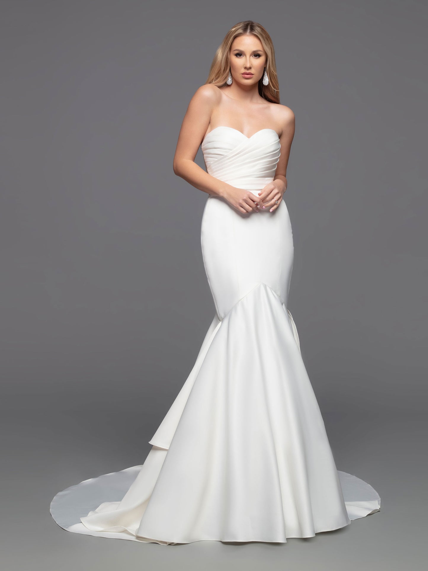 The Davinci Bridal 50808 Long fitted Strapless satin mermaid wedding dress boasts a beautiful modern design with a traditional flair. Its fit & flare silhouette is enhanced by an opaque ruched front bodice and a romantic ruffled mermaid skirt with a sheer back bodice. This stylish design is finished with covered buttons and a tiered back skirt, culminating in a chapel train.  Sizes: 2-20  Colors: Ivory, White