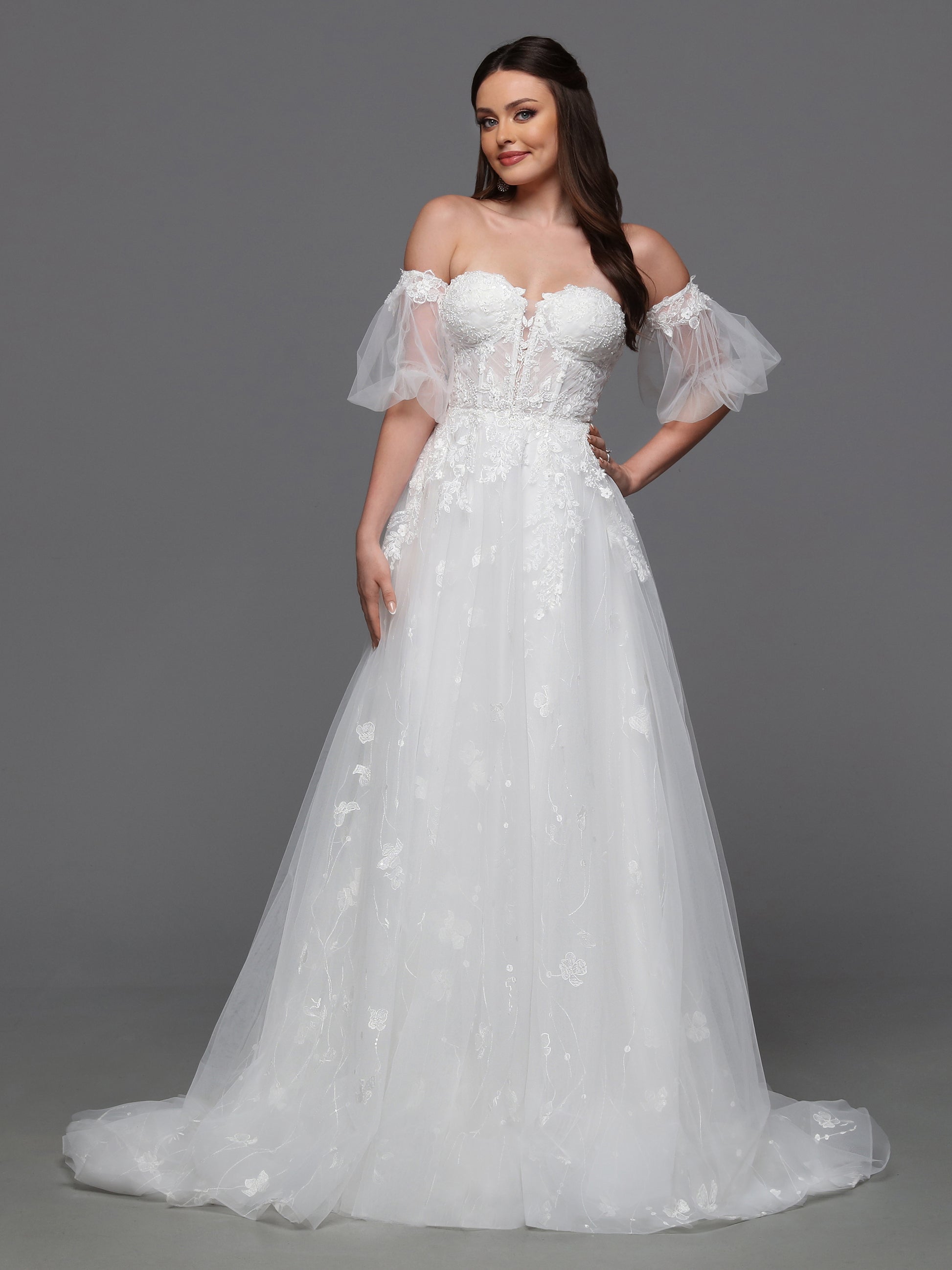 Make a statement on your special day with the Davinci Bridal 50836 A line Puff Sleeve Wedding Dress. The sheer corset enhances your silhouette while the beaded accents add a touch of glamour. With a slit for effortless movement and luxurious puddle sleeves, this dress exudes elegance and sophistication. Flirty and fashionable, this ball gown wedding dress has a sheer lace bodice, peek-a-boo slit skirt and delicate detachable sleeves.