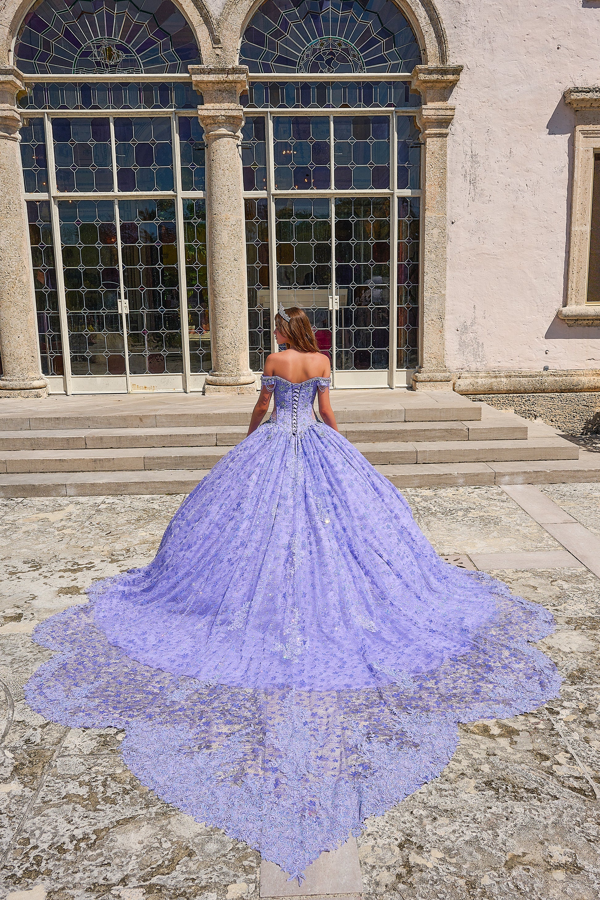 Be the belle of the ball in the Amarra 54220 Quinceanera Ball Gown. This stunning formal dress features a sheer crystal lace train and fringe, for a unique and eye-catching look. The off the shoulder design adds a touch of elegance and the perfect amount of skin. Stand out in style. Unleash your inner princess with our enchanting lace ball gown! Crafted with a dreamy lace fabric adorned with detailed floral pattern