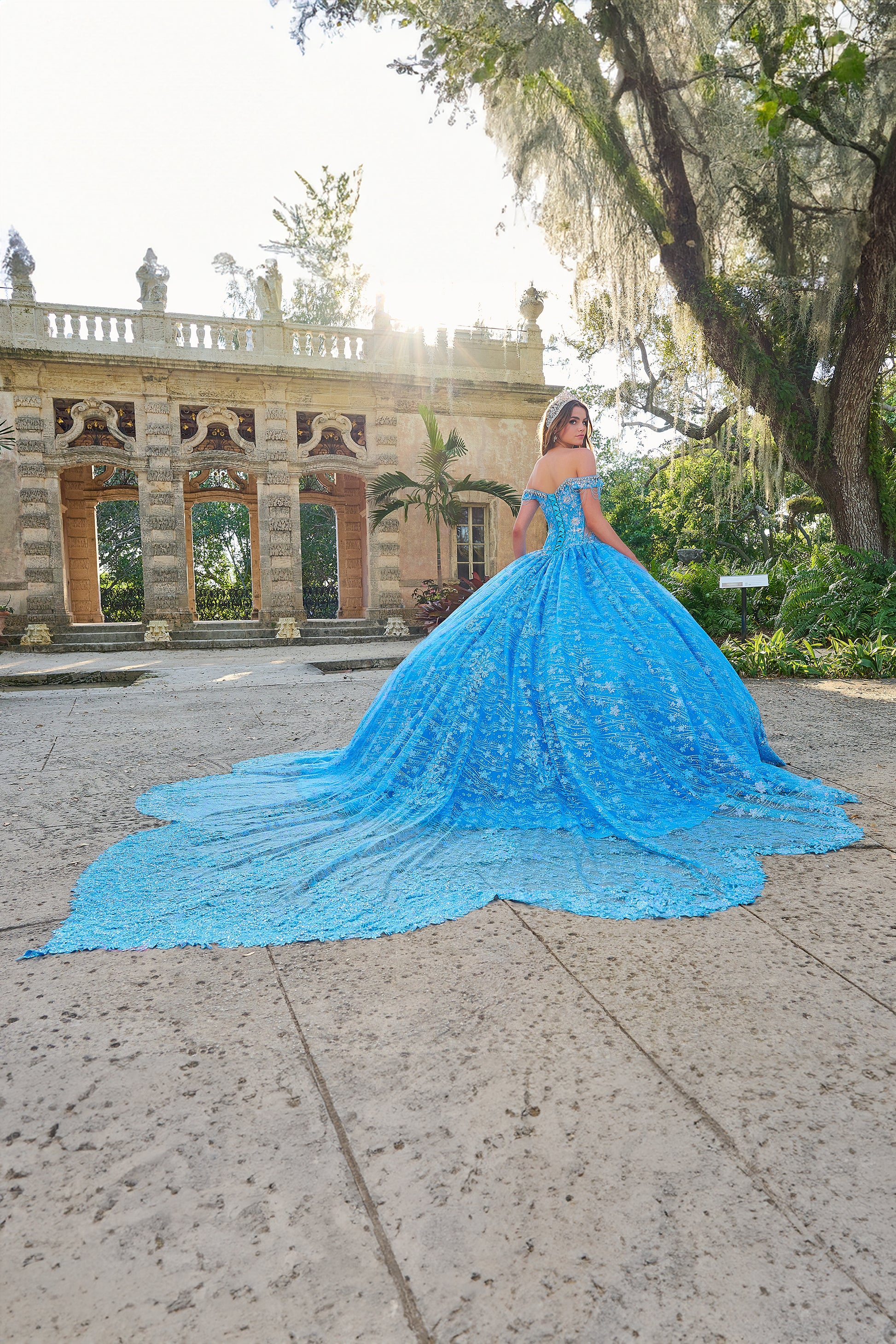 Be the belle of the ball in the Amarra 54220 Quinceanera Ball Gown. This stunning formal dress features a sheer crystal lace train and fringe, for a unique and eye-catching look. The off the shoulder design adds a touch of elegance and the perfect amount of skin. Stand out in style. Unleash your inner princess with our enchanting lace ball gown! Crafted with a dreamy lace fabric adorned with detailed floral pattern