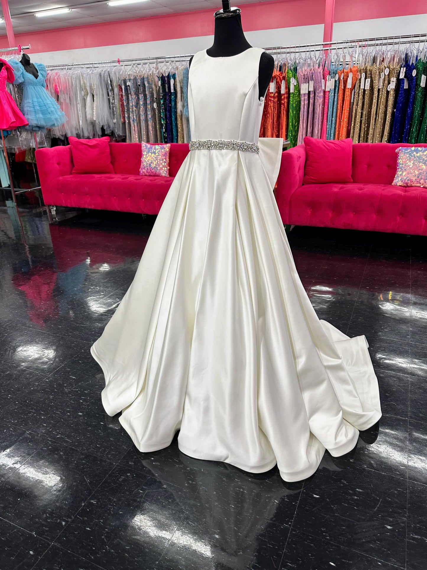 This Ashley Lauren 8079 Size 12 Ivory Long satin A Line girls Pageant Dress features an elegant crew neckline, a crystal encrusted waistline, and an A-line skirt that is complemented by a detachable bow at the back. Perfect for formal occasions, this high-quality gown will make your little girl look beautiful.