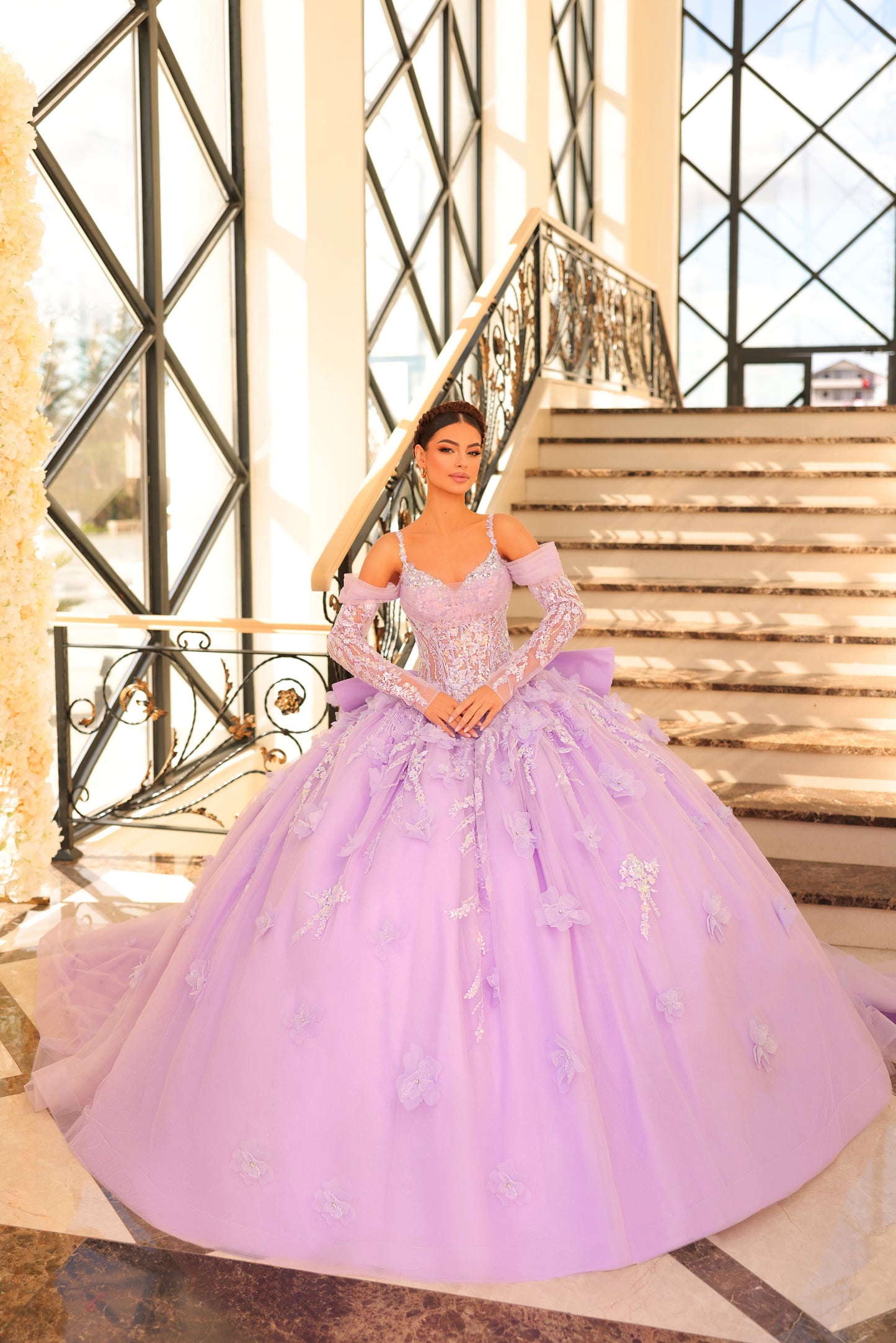 Amarra 54204 Quinceanera Dress Train Long Sleeve Bow Flowers Sequins Ballgown off the Shoulder Crafted from luxurious tulle, this gown is adorned with intricate embroidery and embellishments that shimmer with every step you take. The semi-sweetheart neckline frames your collarbone and upper chest with elegance, while the detachable lace sleeves add drama and romance to the overall design.