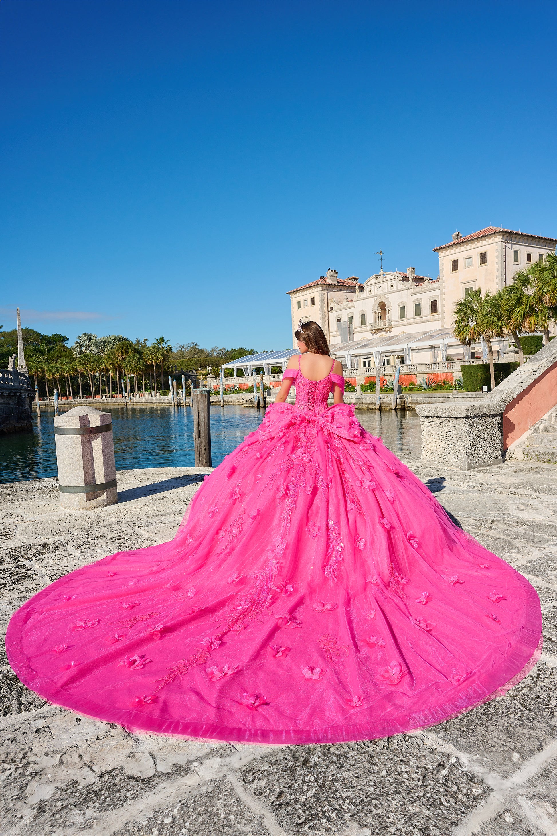 Amarra 54204 Quinceanera Dress Train Long Sleeve Bow Flowers Sequins Ballgown off the Shoulder Crafted from luxurious tulle, this gown is adorned with intricate embroidery and embellishments that shimmer with every step you take. The semi-sweetheart neckline frames your collarbone and upper chest with elegance, while the detachable lace sleeves add drama and romance to the overall design.