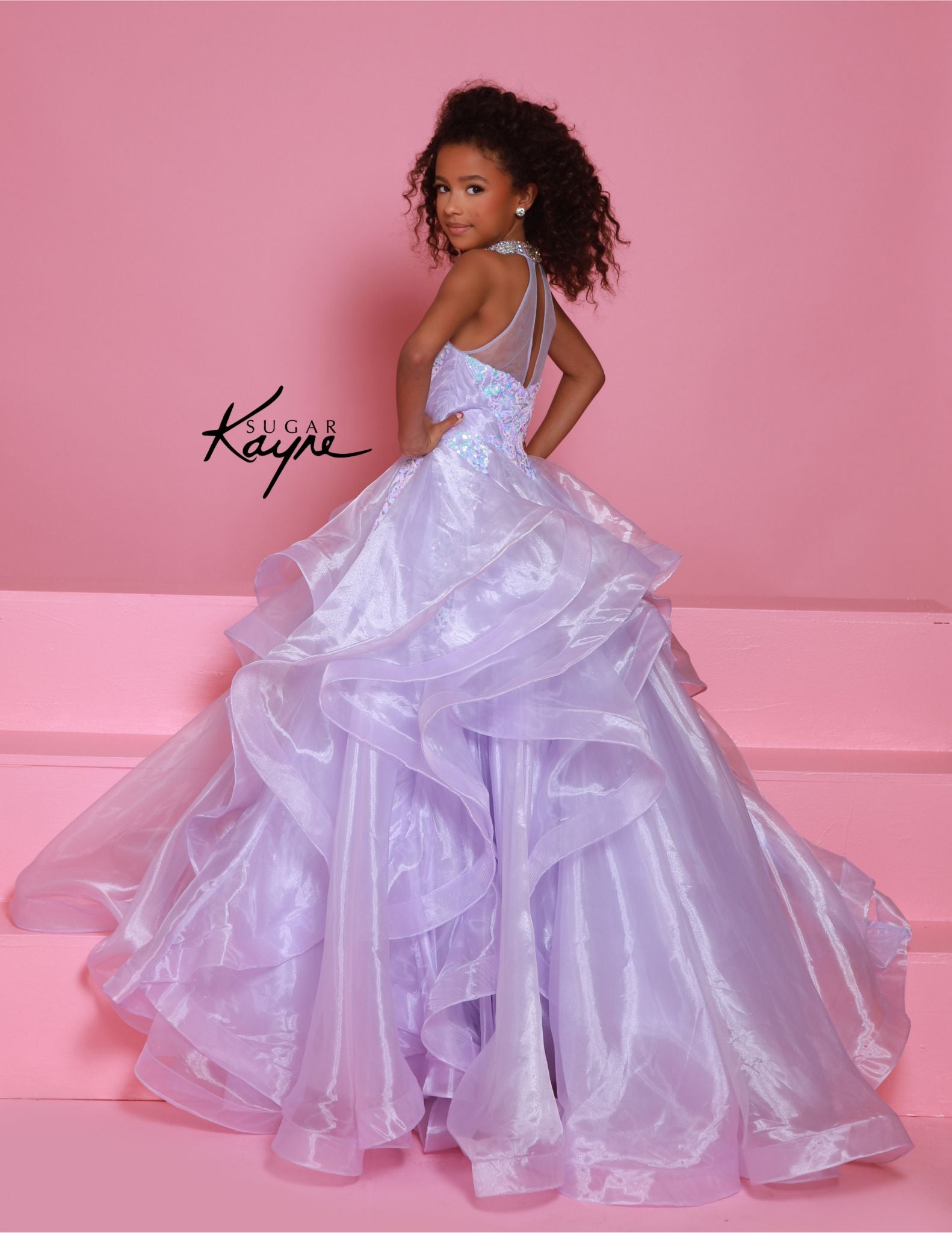 Dress to impress in the Sugar Kayne C371 Pageant Dress. This stunning A-line ballgown features sequin and ruffle details, a high neck, and layered skirt. Perfect for any pageant, this dress will make you stand out from the competition with its elegant and eye-catching design. Elevate your pageant game with Sugar Kayne. Embody elegance and glamour with this dazzling sequin mesh ballgown, designed to make you sparkle on stage. Featuring a halter neck with shimmering beading that highlights your neckline, and 