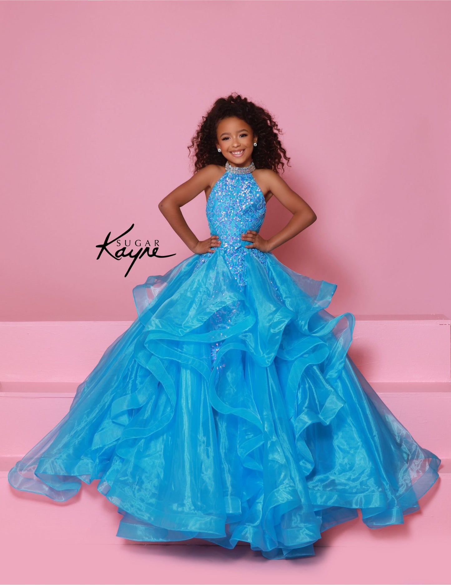 Dress to impress in the Sugar Kayne C371 Pageant Dress. This stunning A-line ballgown features sequin and ruffle details, a high neck, and layered skirt. Perfect for any pageant, this dress will make you stand out from the competition with its elegant and eye-catching design. Elevate your pageant game with Sugar Kayne. Embody elegance and glamour with this dazzling sequin mesh ballgown, designed to make you sparkle on stage. Featuring a halter neck with shimmering beading that highlights your neckline, and 