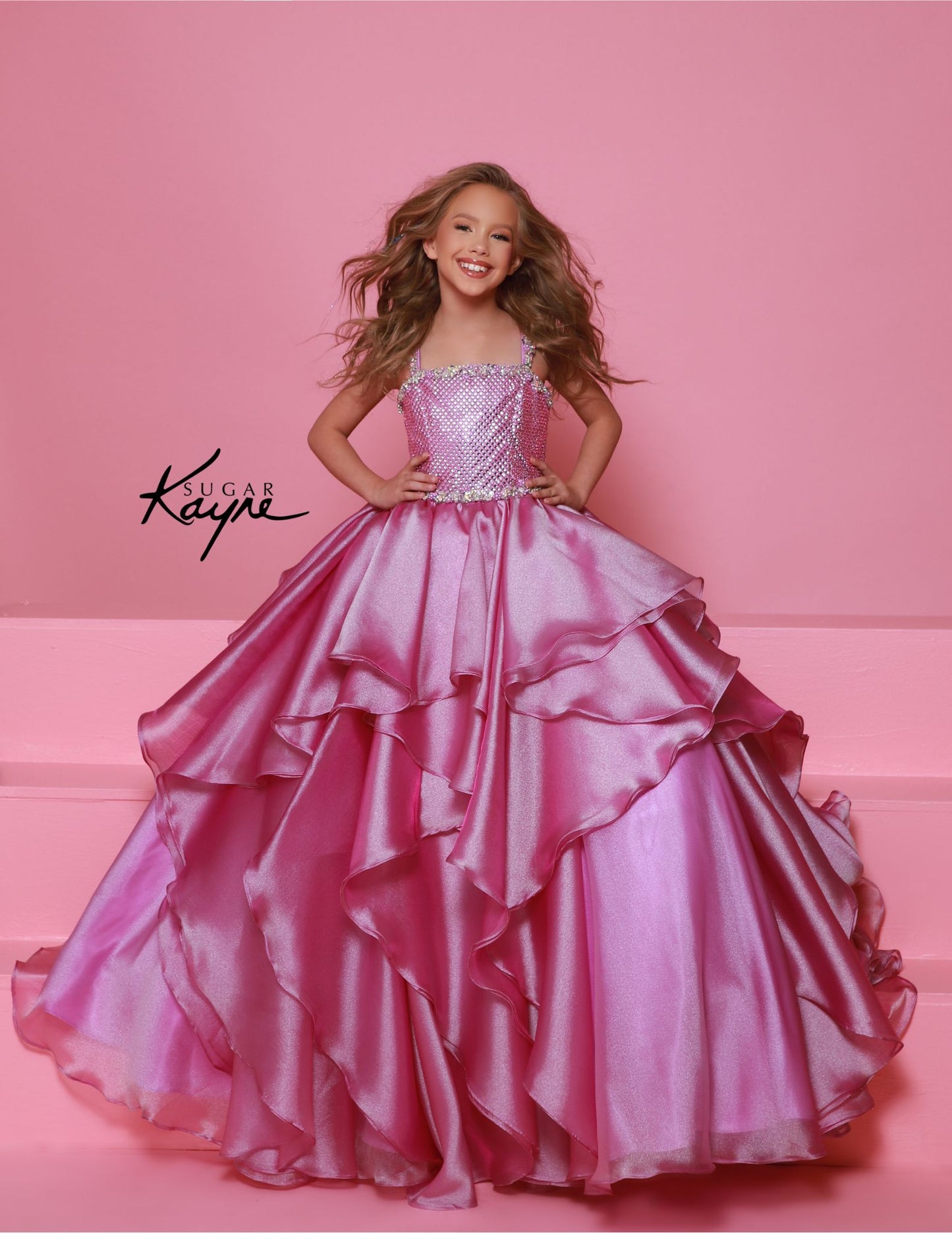 Step onto the pageant stage with confidence in the Sugar Kayne C383 Girls Pageant Dress. This stunning ballgown features a crystal bodice that will shimmer and shine under the lights, while the ruffle detail adds a touch of playful elegance. The layered skirt adds volume and movement, making you the star of the show. Make a dramatic statement at your next pageant with this stunning diamond mesh dress. The ruffled shimmer organza skirt completes the look, offering a perfect blend of elegance and flair.

Size