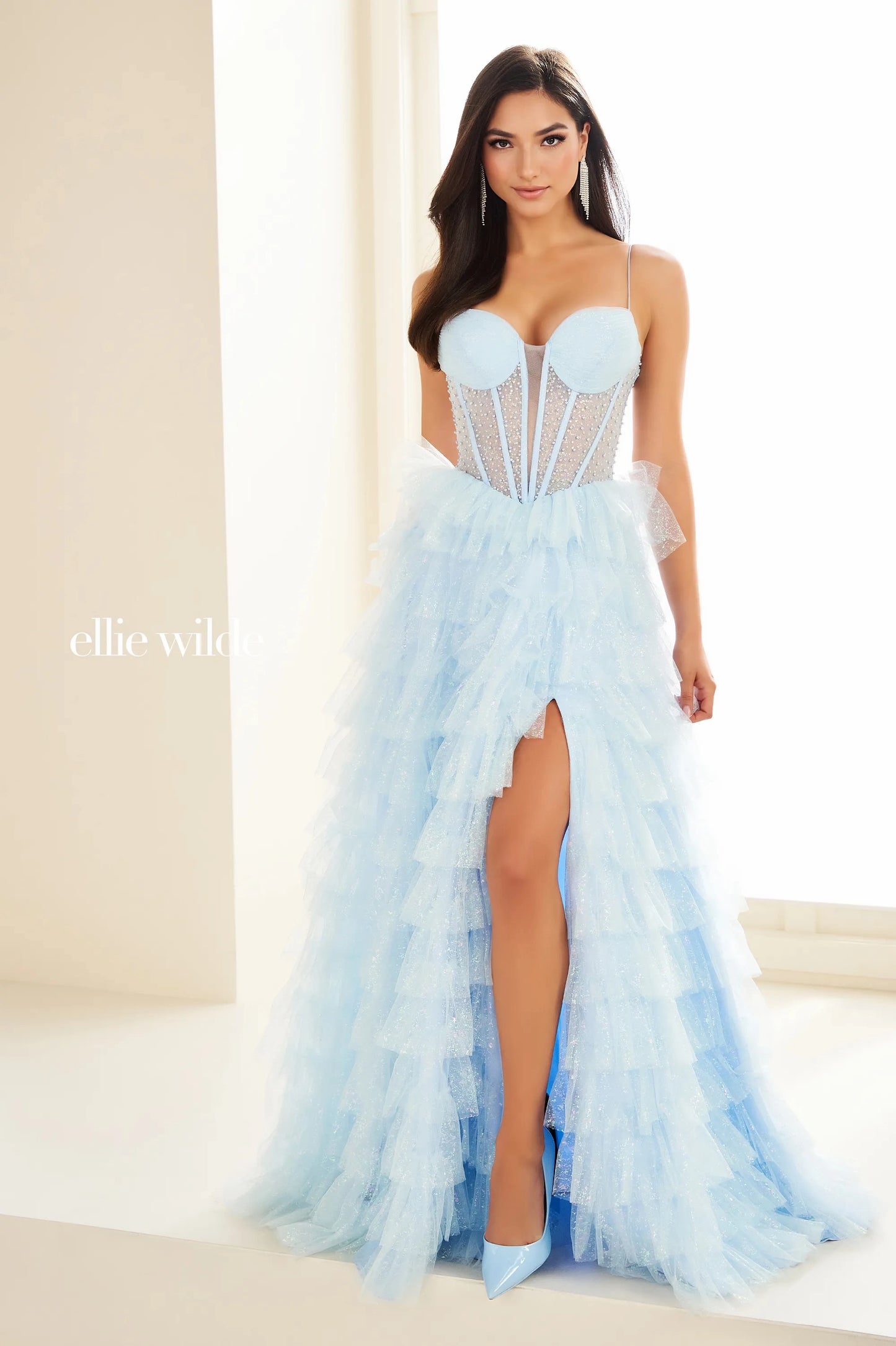 Expertly designed by Ellie Wilde, this prom dress EW36029 features a sheer corset and layered slit for a stunningly elegant look. The shimmering pearl details and pageant-worthy style make it a perfect choice for any formal event. Elevate your style with this statement gown. Layered maxi slit shimmer skirt.