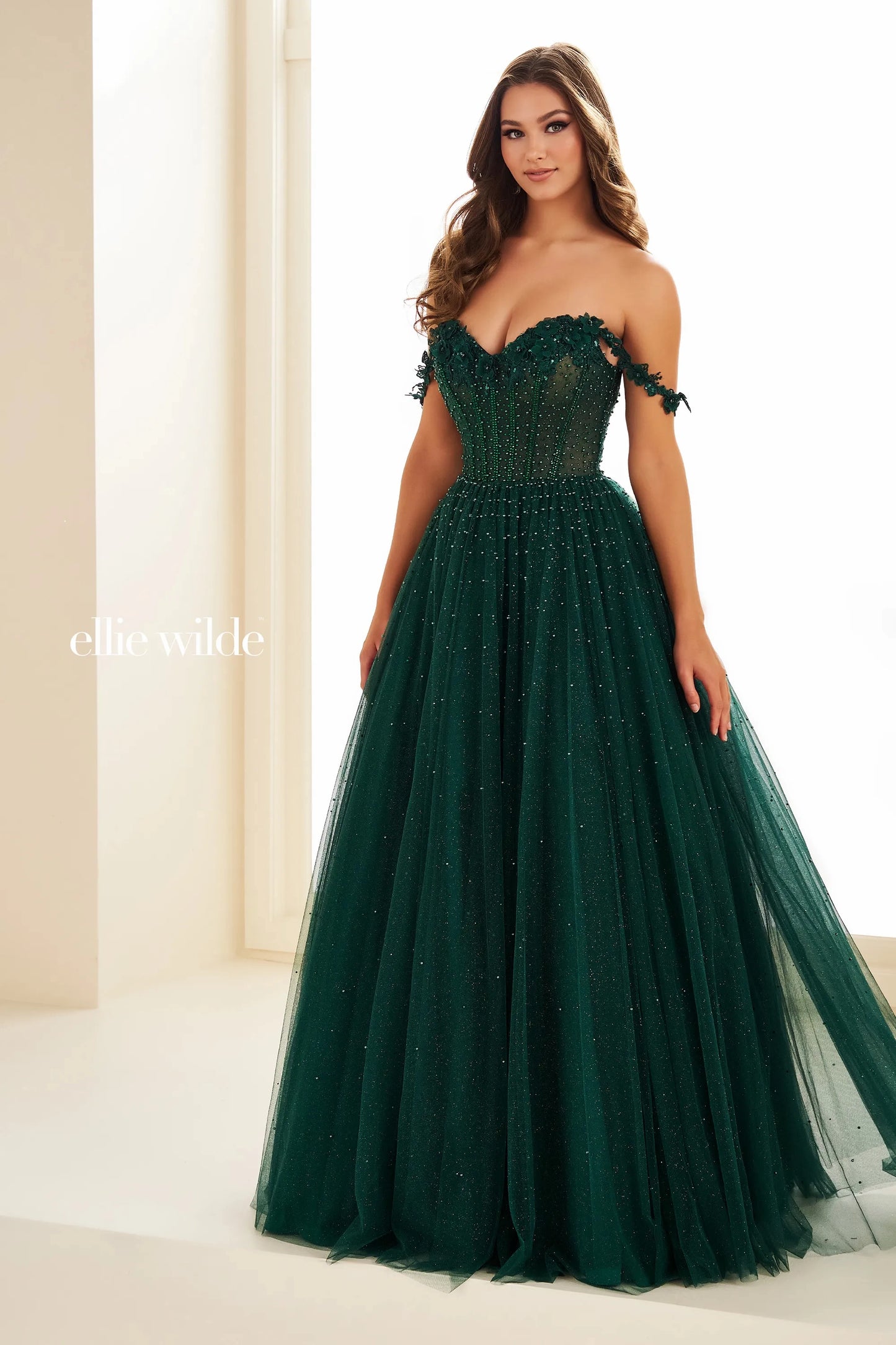 Be the belle of the ball in the Ellie Wilde EW36071 prom dress. This long A line gown features a sheer lace corset bodice and elegant off the shoulder neckline. Perfect for any formal event, this dress will make you feel confident and beautiful. Crystals scattered through tulle a line skirt.